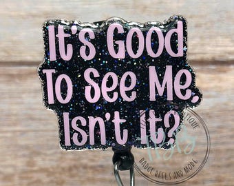 May include: A black glitter badge reel with the text "It's Good To See Me, Isn't It?" in pink lettering. The badge reel has a clear plastic holder and a retractable cord.