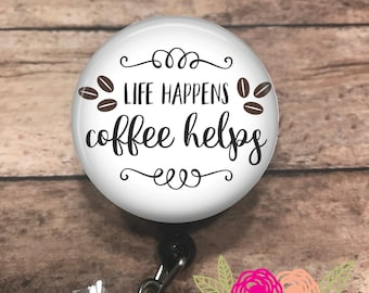 Könnte beinhalten: Ein weißes Ausweis-Jojo mit dem Text "LIFE HAPPENS coffee helps" in schwarzer Schrift, verziert mit Kaffeebohnen-Illustrationen. Das Jojo hat ein einziehbares Kabel und ein Blumendesign.