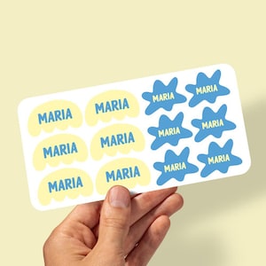 May include: A rectangular sticker sheet featuring twelve individual adhesive labels. Six labels are pale yellow rounded shapes with the name MARIA printed in blue. Six labels are blue irregular splash shapes with the name MARIA in yellow.