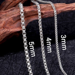 May include: Three silver chains of different widths, 3mm, 4mm, and 5mm, laid out on a wooden surface.