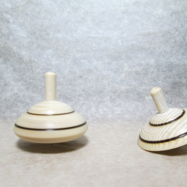 Set of two white and black spinning tops in ashwood, manual woodturning