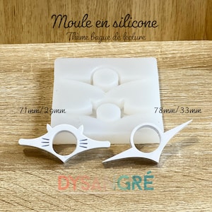 Può includere: Uno stampo in silicone bianco per realizzare anelli da lettura, con il testo "Moules en silicone" e "Thème bague de lecture". Vengono mostrati due anelli da lettura bianchi finiti, uno di 71 mm x 29 mm e l'altro di 78 mm x 33 mm.
