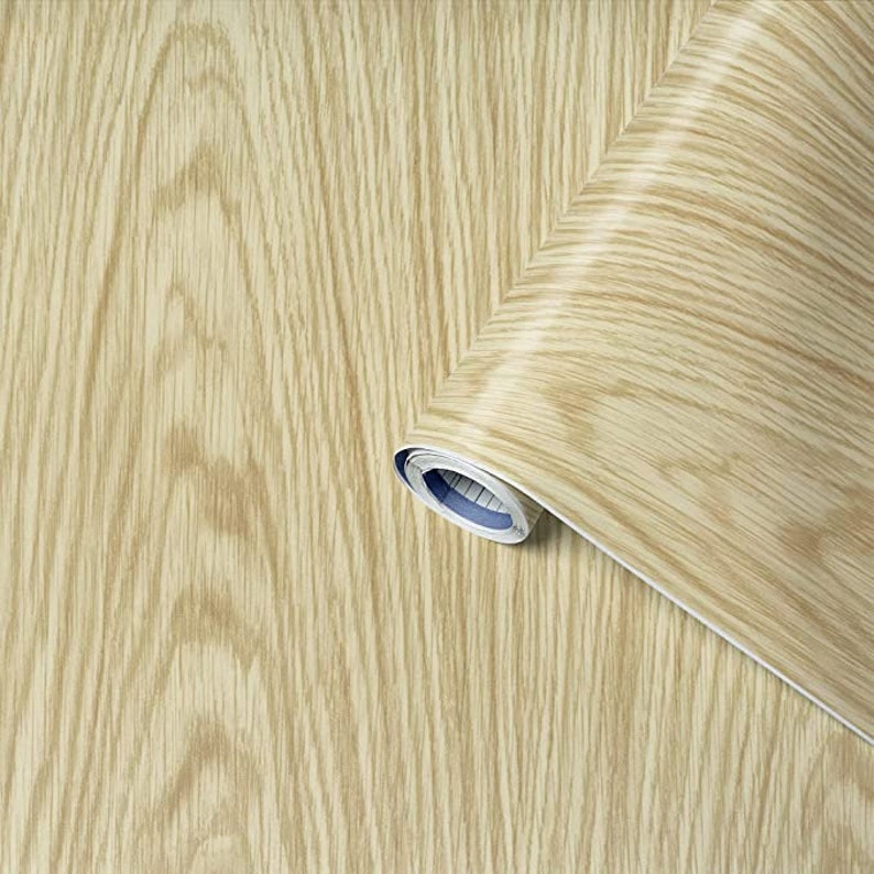 May include: A roll of wood-grain contact paper. The paper is light brown with a wood grain pattern. The roll is partially unrolled, showing the paper's texture.