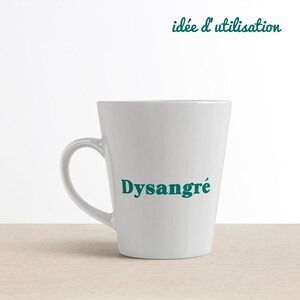 May include: White ceramic mug with a teal green inscription that reads "Dysangr&eacute;".