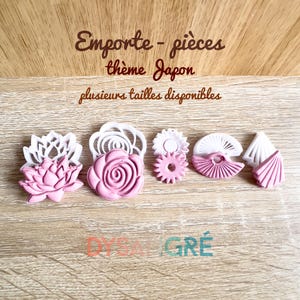 Puede incluir: Un conjunto de cortadores de galletas rosas y blancos con temática japonesa. Los cortadores incluyen formas de flor de loto, rosa, engranaje y abanicos. El texto en la imagen dice "Emporte-pièces thème Japon" y "plusieurs tailles disponibles".