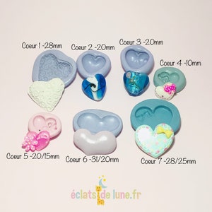 Puede incluir: Siete moldes de silicona en forma de corazón para manualidades. Los moldes son de varios tamaños, que van desde 10 mm hasta 31 mm. Los moldes son de color azul claro y morado. La imagen también muestra ejemplos de manualidades terminadas en forma de corazón hechas con los moldes.