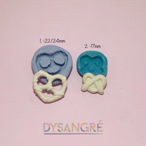 Puede incluir: Dos moldes de silicona para hacer pretzels en forma de corazón. El molde más grande es de 22/24 mm y el más pequeño de 17 mm. Los moldes son azules y blancos.