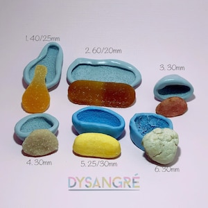 May include: Six silicone moulds for making candy or other treats. The moulds are blue and have different shapes, including a spoon, a rectangle, an oval, and a heart. The moulds are labelled with measurements in millimetres. The text "DYSANGRÉ" is printed in rainbow colours at the bottom of the image.