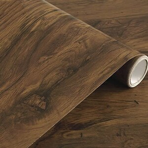 May include: A roll of brown wood-grain contact paper. The paper has a realistic wood grain pattern.