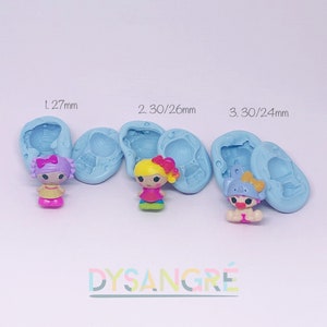 Puede incluir: Tres moldes de silicona para hacer pequeñas figuritas. Los moldes son de color azul claro y presentan diferentes diseños. El primer molde es de 1,27 mm, el segundo de 2,30/26 mm y el tercero de 3,30/24 mm. Los moldes están etiquetados con las medidas en milímetros. El texto "DYSANGRÉ" es visible en la parte inferior central de la imagen.