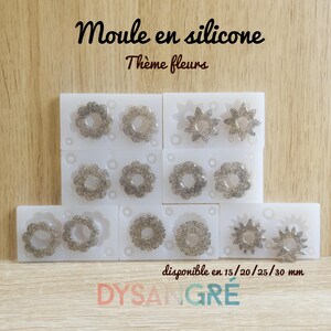 Peut inclure: Moules en silicone blancs avec des motifs floraux. Les moules sont remplis d'une matière argentée scintillante, présentant divers motifs floraux. Le texte sur l'image indique "Moule en silicone Thème fleurs" et "disponible en 15/20/25/30 mm". La marque "DYSANGRÉ" est également visible.