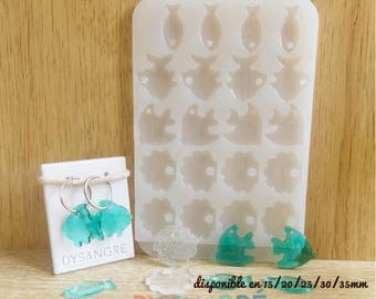 May include: A white silicone mold with various fish and flower shapes, alongside finished teal fish-shaped earrings on a white card. The text "Moule en silicone" and "DYSANGRE" are visible. The text "disponible en 15/20/25/30/35mm" is also visible.
