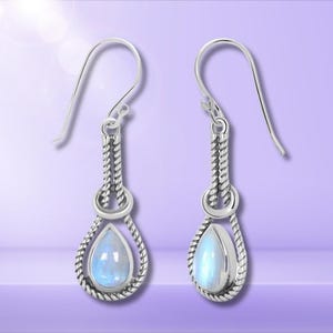 May include: Silver dangle earrings featuring a teardrop-shaped moonstone gemstone. The earrings have a twisted rope design.
