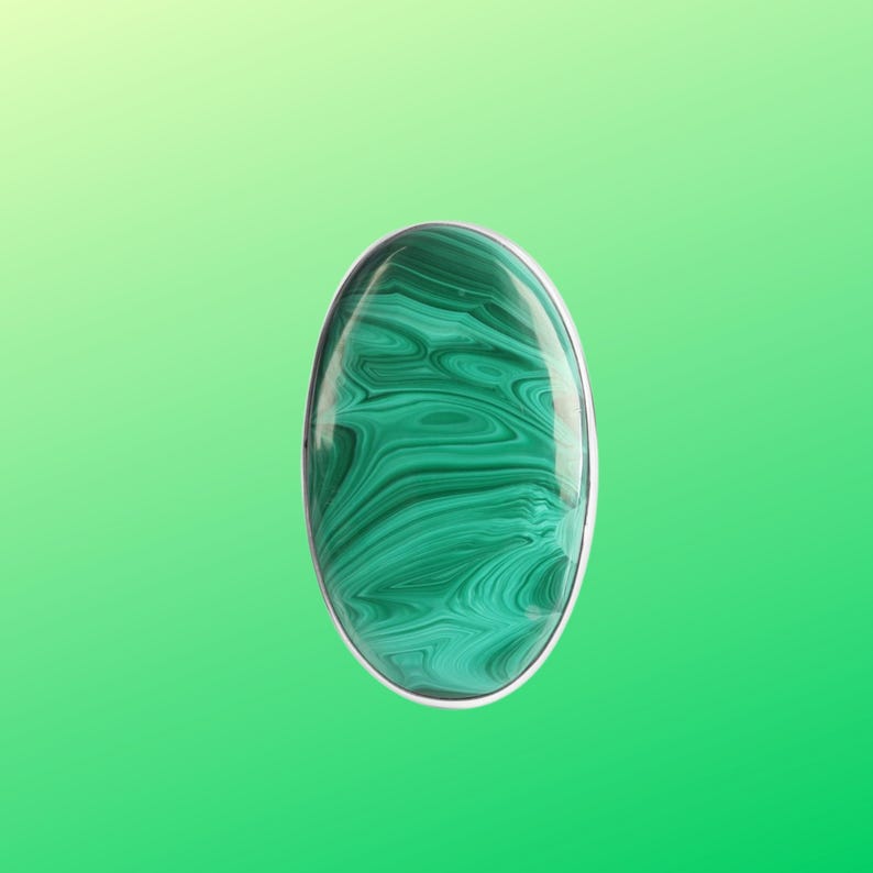 May include: A green malachite gemstone cabochon set in a silver ring.
