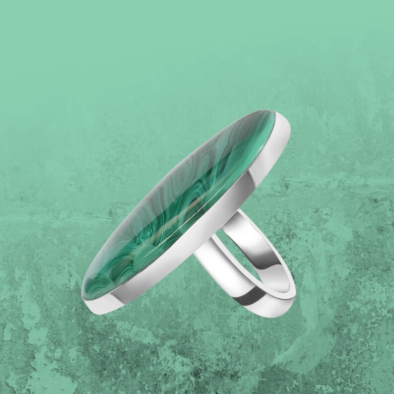 May include: A silver ring with a large oval green malachite stone.