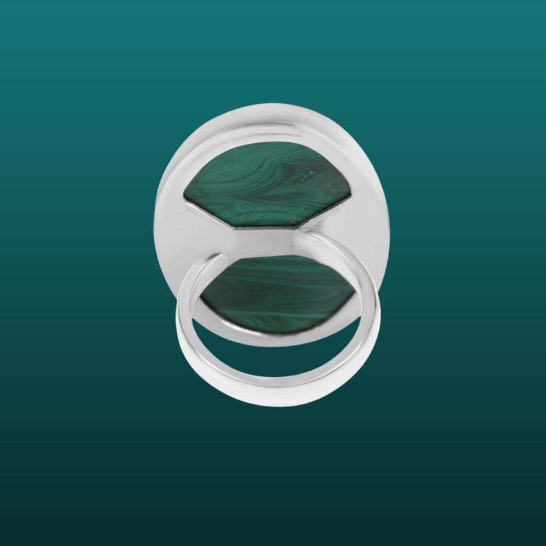 May include: A silver ring with a green malachite stone set in the center. The ring is shown from the back, revealing the setting and the band.