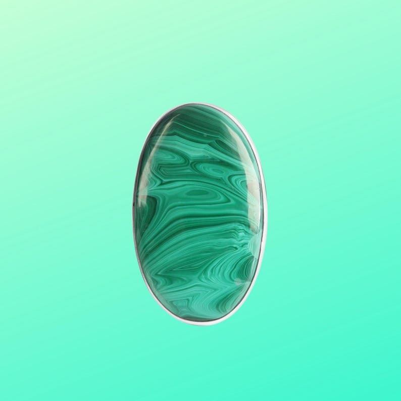 May include: A green malachite gemstone ring with a silver setting. The stone has a swirling pattern of green and black.