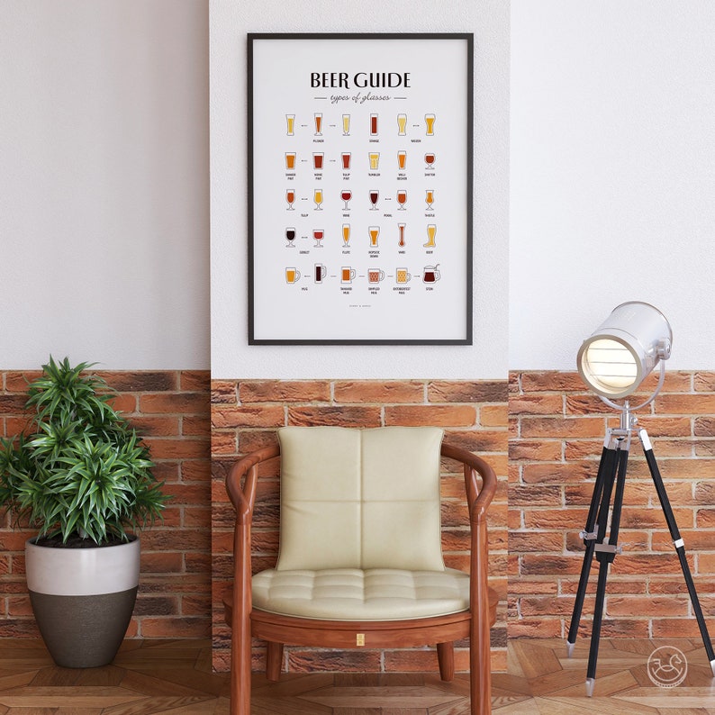 May include: A black framed poster with the title "BEER GUIDE: types of glasses" and illustrations of different beer glasses. The poster is hanging on a white wall above a brown leather chair with a wooden frame. A silver spotlight on a black tripod is in the corner of the image.