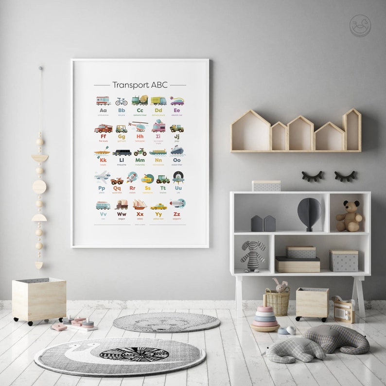 K&ouml;nnte beinhalten: Ein farbenfroher Alphabet-Chart mit verschiedenen Verkehrsmitteln, darunter Autos, Lastwagen, Flugzeuge, Boote und Z&uuml;ge. Der Chart ist gerahmt und h&auml;ngt an einer grauen Wand in einem Kinderzimmer oder Spielzimmer.