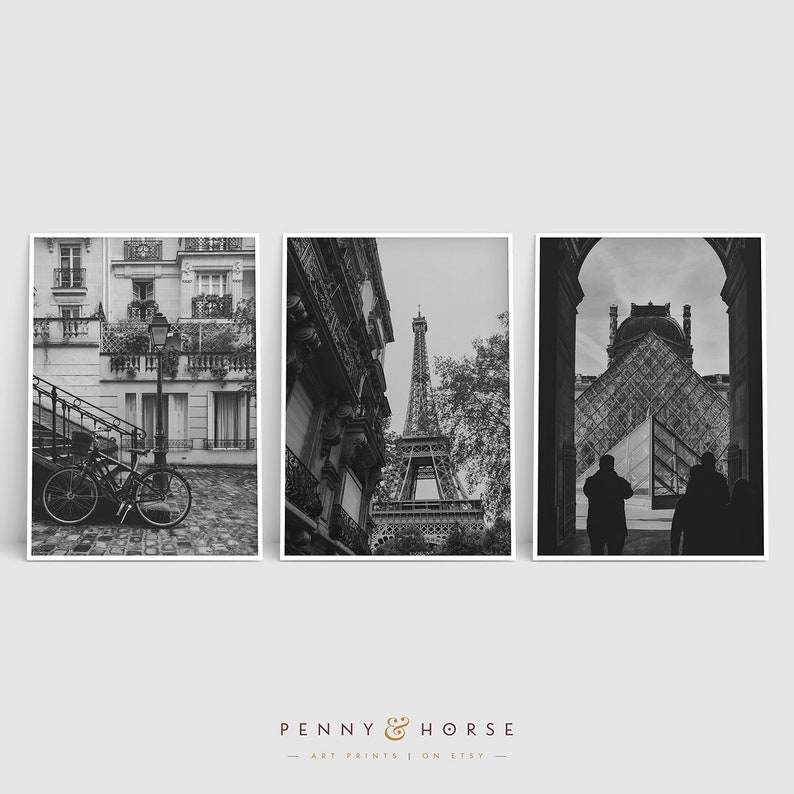 May include: A set of three black and white photographs featuring Parisian landmarks. The first photo shows a bicycle parked on a cobblestone street in front of a building with a balcony. The second photo shows the Eiffel Tower from a street-level perspective. The third photo shows a view of the Louvre Museum from inside an archway.