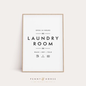 May include: A framed laundry room sign with the text "OPEN 24 HOURS" and "LAUNDRY ROOM" in a minimalist black and white design. Below the text are icons for washing, drying, and folding. The sign is from Penny & Horse.