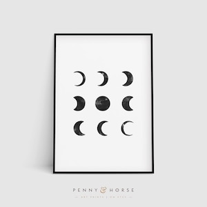 May include: A black and white printable art print featuring a minimalist design of nine moons in different phases. The print is framed in a black frame and has the text "PENNY & HORSE ART PRINTS | ON ETSY" at the bottom.