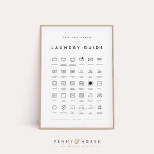 May include: A framed laundry guide print with black and white care label symbols. The print includes text that reads "Care Label Symbols" and "Laundry Guide". The bottom of the print has the text "Penny & Horse Art Prints on Etsy".