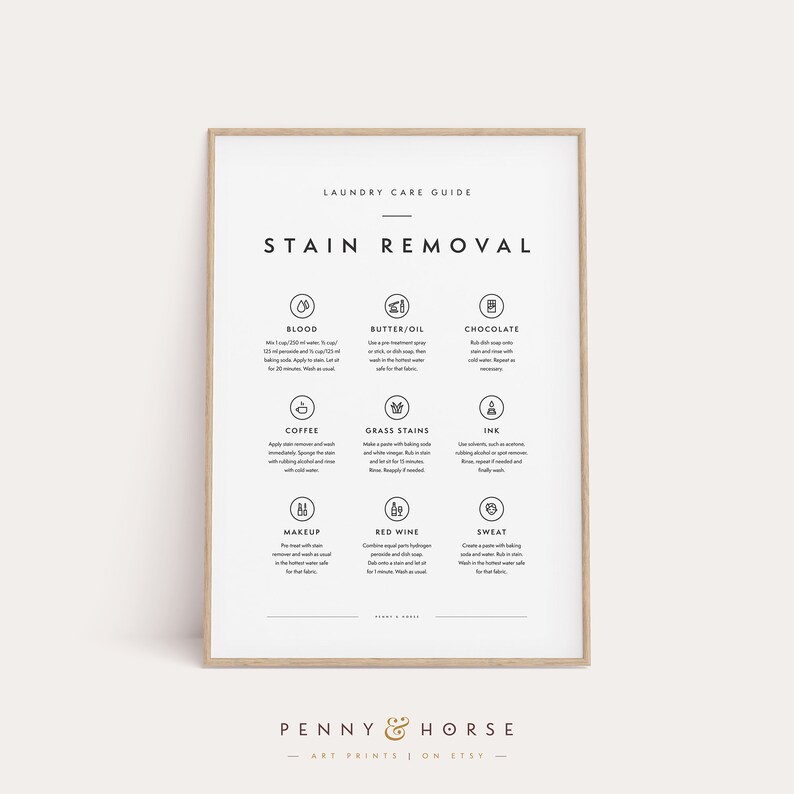 May include: A framed laundry care guide print with stain removal instructions. The guide includes steps for removing blood, butter/oil, chocolate, coffee, grass stains, ink, makeup, red wine, and sweat. The print has a light wood frame and the text "Penny & Horse" at the bottom.
