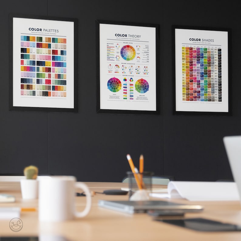 May include: Three framed posters on a black wall. The posters are titled "Color Palettes", "Color Theory", and "Color Shades". Each poster features a different color chart.