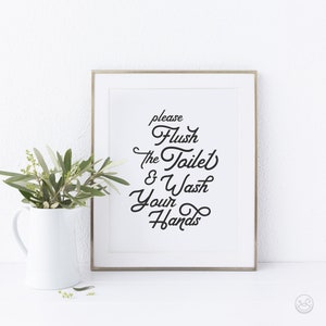 May include: A white framed print with black text that reads "please flush the toilet & wash your hands".