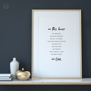 May include: A framed print with a gold frame and white background. The print features the text "in this house we are real, we make mistakes, we say 'I'm sorry', we give second chances, we have fun, we give hugs, we forgive, we do really loud, we are patient, we love".