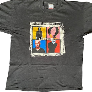 Könnte beinhalten: Schwarzes T-Shirt mit einem Band-Motiv, das vier Personen in bunten Quadraten zeigt. Der Bandname "garbage" ist in weißen Buchstaben unter den Quadraten gedruckt.