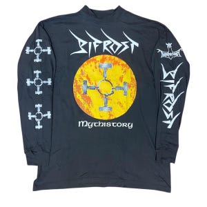 May include: Black long-sleeve shirt with a mock neck. The shirt features white graphics on the sleeves and a large design on the front, including the word "Bifrost" and the word "Mythistory". The front design includes a yellow circle with a cross.