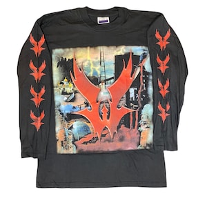 May include: Black long-sleeve t-shirt with a red and black graphic print of a stylized creature with lightning bolts and a cityscape in the background. The sleeves have a repeating pattern of red stylized creatures.
