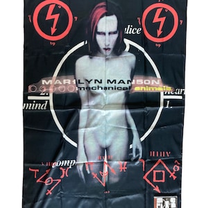May include: A black flag with a red circle and lightning bolt, the words "Marilyn Manson", "mechanical animals", and "mind" in white text, and a nude figure in the center. The figure has red hair and is wearing a black choker.