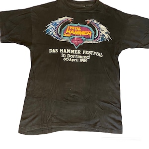 Peut inclure: T-shirt noir avec un graphique d'une créature ailée et le texte "Metal Hammer Crash" et "Das Hammer Festival in Dortmund 30 April 1989".