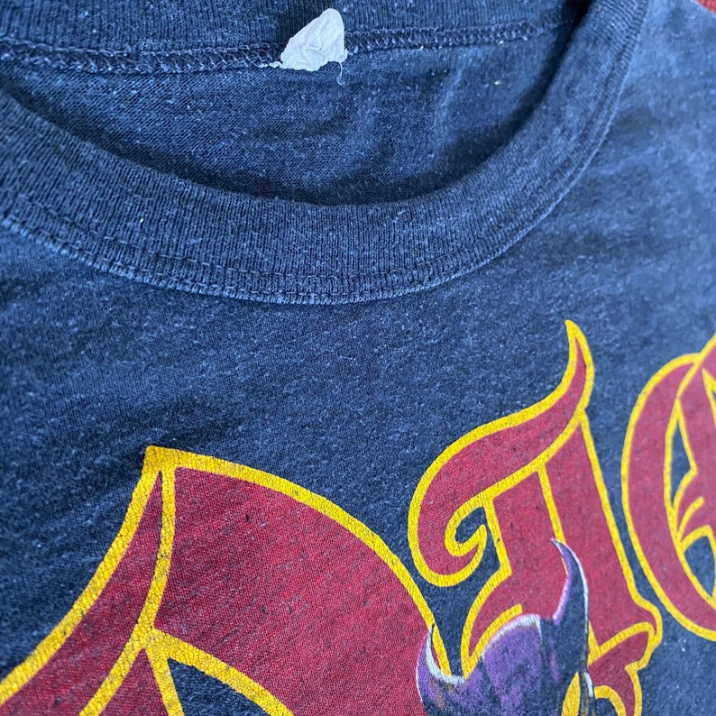 May include: A dark blue t-shirt with a red and yellow graphic design. The graphic design features a stylised image of a dragon with a purple head and wings.