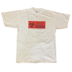May include: White t-shirt with a red and black biohazard symbol and the text "Biological Hazard" and "BIOHAZARD".