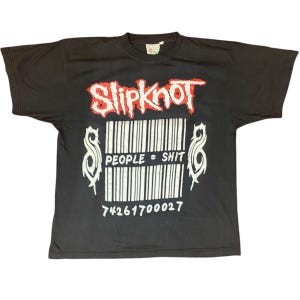 May include: Black t-shirt featuring the band name "Slipknot" in red and white, above a barcode design with the text "PEOPLE = SHIT" and the number "74261700027" in white. The shirt has short sleeves and a crew neck.