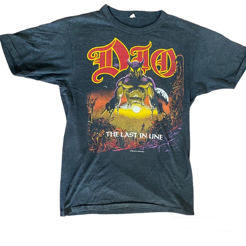 May include: Black t-shirt featuring a red and yellow graphic of a band called "DIO" with the words "The Last in Line".
