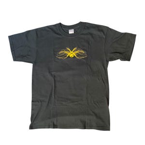 May include: A dark grey t-shirt with a yellow graphic of a stylised letter "K" with wings.