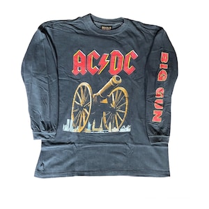 Könnte beinhalten: Schwarzes Langarm-T-Shirt mit einem rot-weißen AC/DC-Logo und einer Kanone. Der rechte Ärmel hat den Schriftzug "BIG GUN" in Rot.