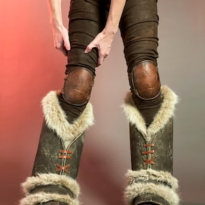 May include: Brown leather trousers with knee pads and fur-lined boots. The boots feature a dark brown leather exterior with tan fur trim and red lacing. The knee pads are a lighter brown leather.