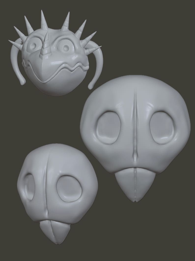 May include: Three grey, stylised, cartoonish creature heads. One has a spiky crown, a horn, and handles. The other two have large eye sockets and a beak-like lower jaw. The heads are on a grey background.
