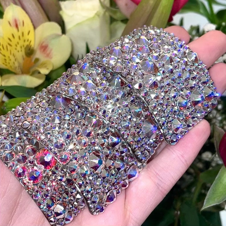 May include: Four silver-toned hair clips with a rainbow iridescent finish. Each clip is covered in small, sparkling rhinestones.