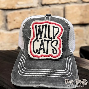 May include: A black and white trucker hat with a red and white patch that says "WILD CATS" in black lettering.