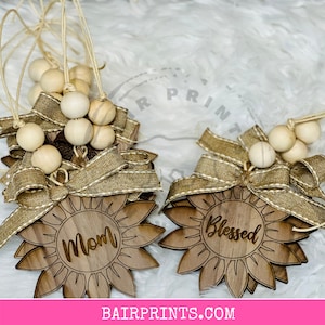 May include: Two wooden sunflower ornaments with burlap bows and wooden beads. One ornament says "Mom" and the other says "Blessed".