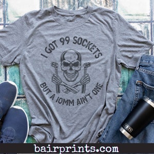 May include: A gray t-shirt with a skull and crossbones graphic. The text on the shirt reads "I got 99 sockets but a 10mm ain't one".