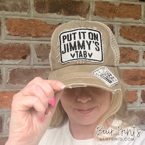 May include: A brown distressed baseball cap with a white patch that says "Put it on Jimmy's VTAB" and a smaller white patch that says "Soooooo Wife".