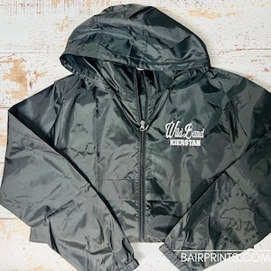 May include: Black hooded windbreaker jacket with a white embroidered logo that says "Wild Band Kierstan". The left sleeve has a black and white logo that says "Bair Prints" with a bear graphic.
